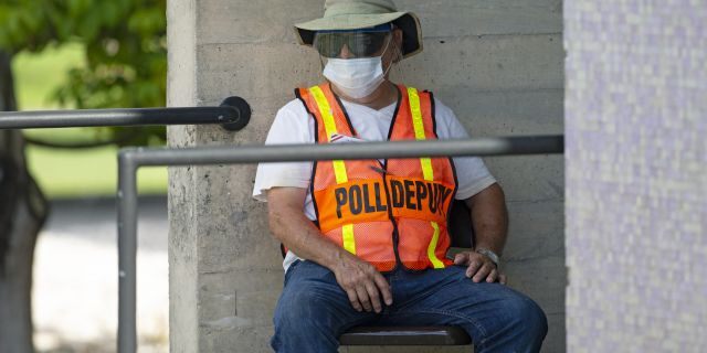 A polling worker waits outside the polling place during early voting for the primary election at the Miami Dade College North Campus in Miami on Sunday, Aug. 9, 2020. (David Santiago/Miami Herald via AP)